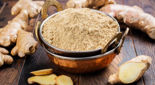 Fresh ginger root and ginger powder in a copper bowl